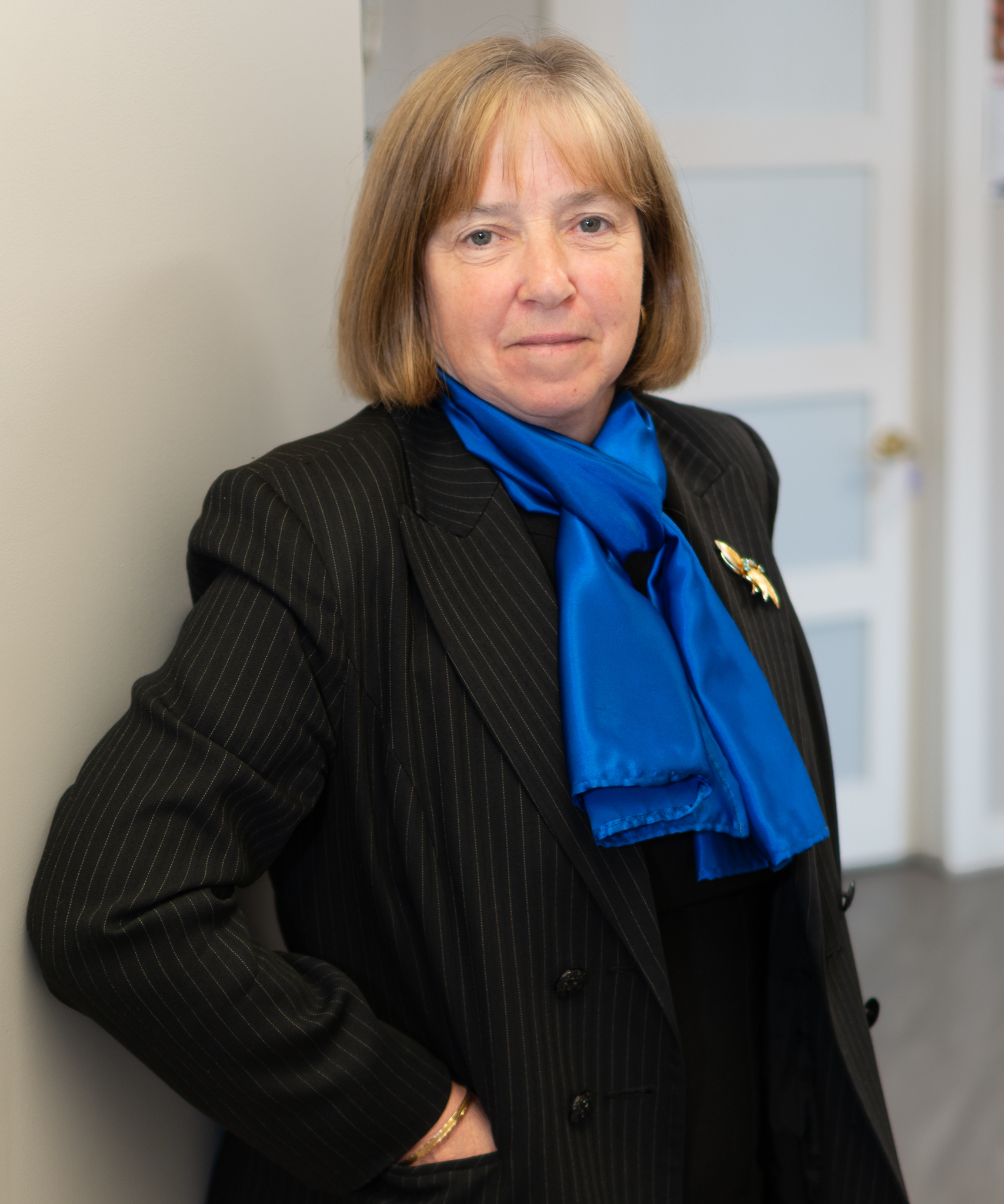 Genevieve Dawson, Associate Consultant at Dawson & Associates IG Private Wealth Management, standing in a professional office setting wearing a dark blazer and blue scarf.