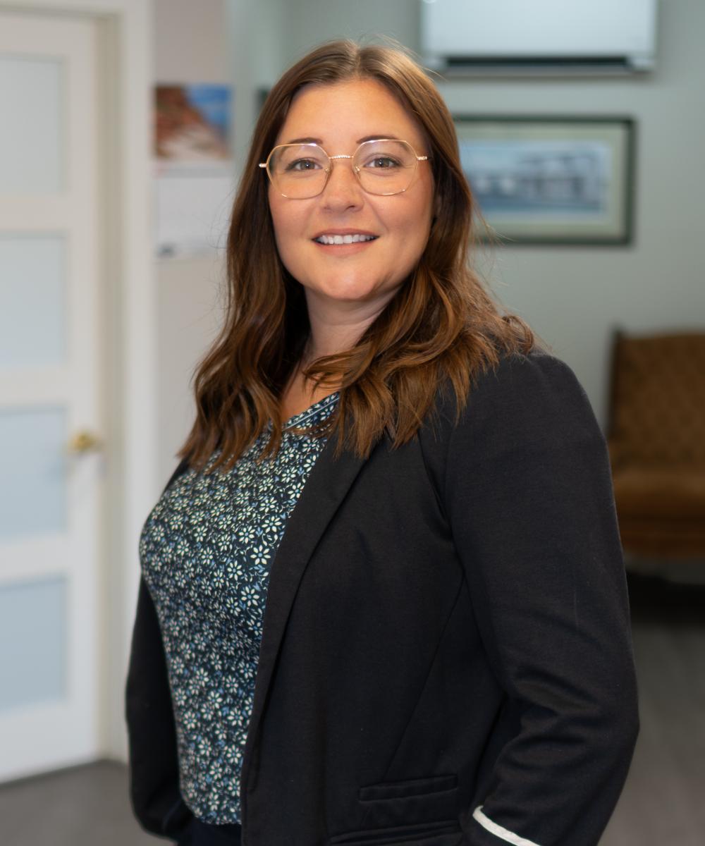 Katie Lee Hutchings, Wealth Advisor at Dawson & Associates IG Private Wealth Management, wearing glasses, a dark blazer, and a patterned blouse in a professional office portrait.